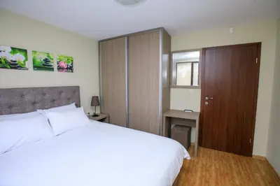 a bedroom with a white bed and a wooden cabinet at Feel at Home in Sandanski