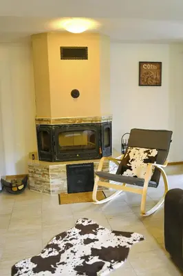 a living room with a fireplace and a chair at КЪЩА ЗА ГОСТИ “НИЯ” in Smolyan