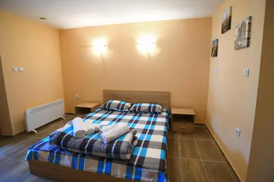 a bedroom with a bed with a blue and white blanket at КЪЩА ЗА ГОСТИ “НИЯ” in Smolyan