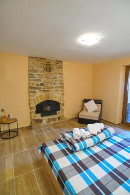 a living room with a bed and a fireplace at КЪЩА ЗА ГОСТИ “НИЯ” in Smolyan