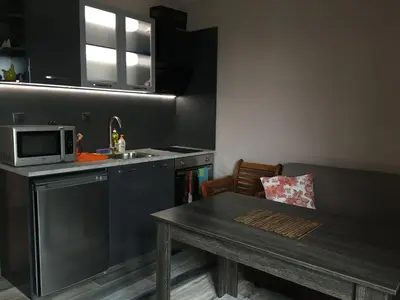 a kitchen with a table and a sink and a microwave at Къща за гости Роял in Sandanski