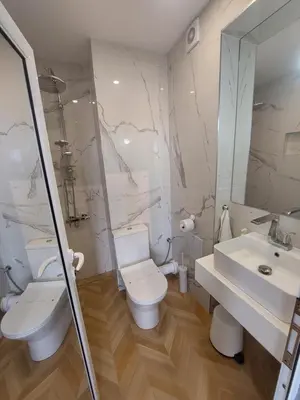 a white bathroom with a toilet and a sink at Студио с вана и гледка в 