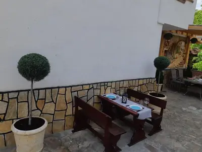 a patio with two tables and two potted trees at Къща Томови,стаи за гости in Devin