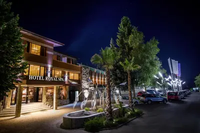 a hotel with palm trees in front of a building at Royal Spa Hotel in Velingrad
