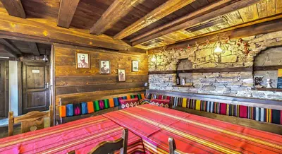 a dining room with a table and a stone wall at Къща Стара Македония in Gostun