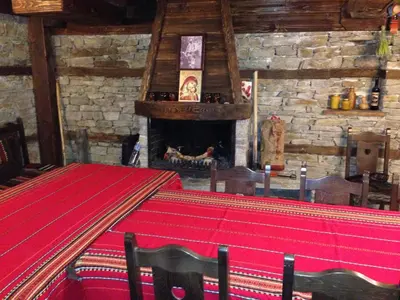 a room with a red table and a fireplace at Къща Стара Македония in Gostun