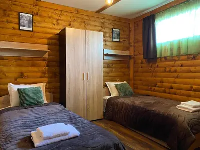two beds in a room with wooden walls at Тихият кът in Sapareva Banya
