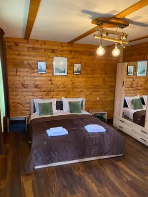 a bedroom with a large bed and wooden walls at Тихият кът in Sapareva Banya