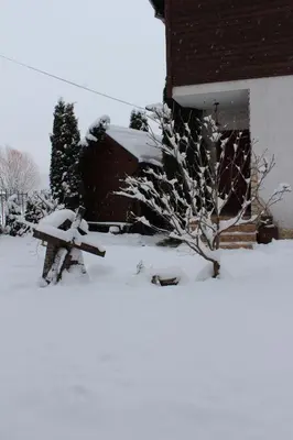 a snow covered bench in front of a house at Къща за гости 