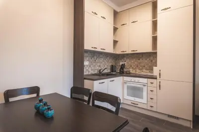 a kitchen with a table and chairs and white cabinets at Semiramis` Suite 2-bedroom Lux Apartment in Sofia