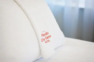 a pillow with a sign on the side of a bed at Plovdiv City Center Hotel in Plovdiv