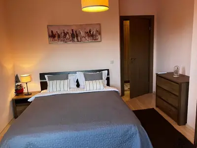 a bedroom with a large bed and a dresser and lamp at Mirabell Apartment Bansko - Mountain View & Fireplace in Bansko