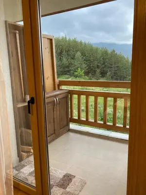 an open door to a balcony with a view of trees at Mirabell Apartment Bansko - Mountain View & Fireplace in Bansko