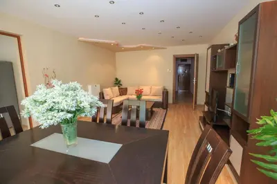 a dining room and living room with a table and flowers at Мария Парк in Sandanski