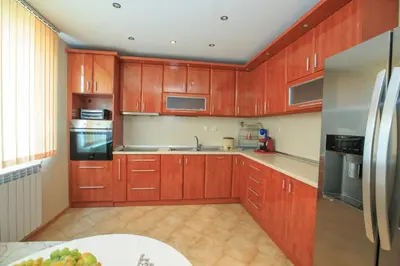 a kitchen with wooden cabinets and a stainless steel refrigerator at Мария Парк in Sandanski