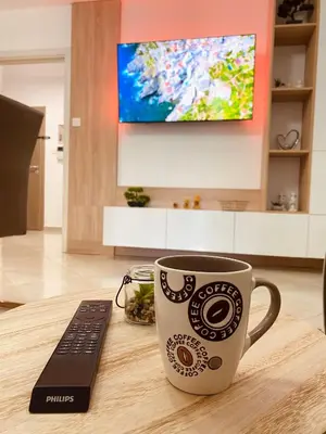 a coffee cup sitting on a table with a remote control at Irina Apartment in Sandanski