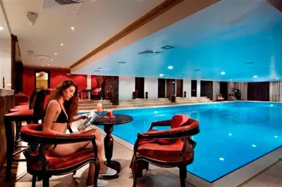 a woman sitting at a table in front of a swimming pool at Grand Monastery Private Apartment in Pamporovo
