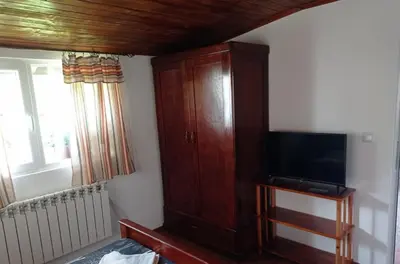a living room with a tv and a wooden cabinet at Семейна къща Лазарови in Sapareva Banya
