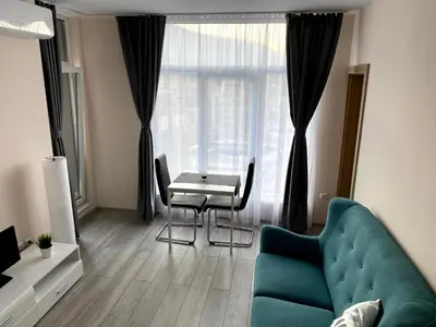 a living room with a blue couch and a table at Mountain View Magenta White apartment in Sofia