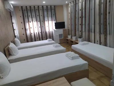 a hotel room with three beds and a television at Каламанди in Asenovgrad