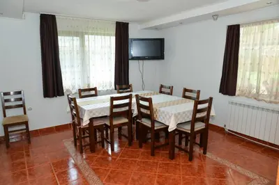 a dining room with a table and chairs and a television at Villa Rila Garden in Beli Iskar