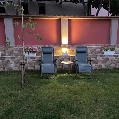 three chairs and a table in a yard at night at Къща за гости детелина - лина in Sapareva Banya
