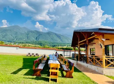 a picnic table in a field with mountains in the background at Къщи за гости “Планински Рай” Mountain Paradise in Resilovo