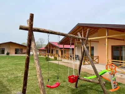 a swing set in a yard with a cross at Къщи за гости “Планински Рай” Mountain Paradise in Resilovo