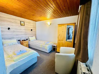 a room with two beds and a chair in it at Къща за гости Даутев Връх in Bansko