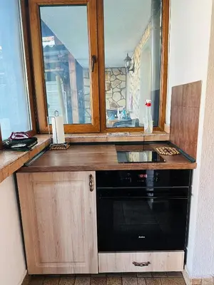 a kitchen with a black dishwasher under a window at Къща за гости Даутев Връх in Bansko
