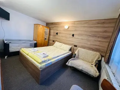 a small bedroom with a bed and a chair at Къща за гости Даутев Връх in Bansko