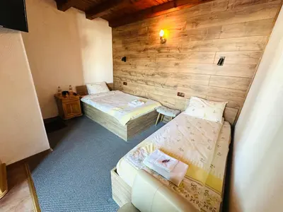 two twin beds in a room with wooden walls at Къща за гости Даутев Връх in Bansko
