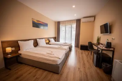 a hotel room with two beds and a television at Family Hotel Konstantinovi in Kyustendil