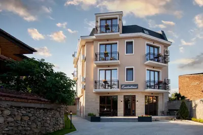 a tall white building with windows and balconies at Family Hotel Konstantinovi in Kyustendil