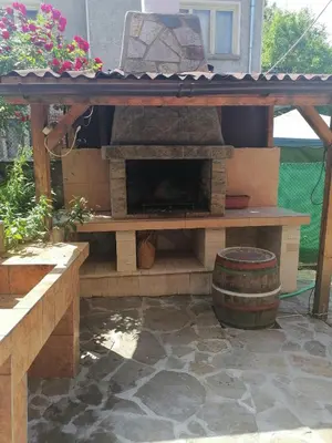 a patio with a stone fireplace and a barrel at Guest House Shipkovo Hills in Shipkovo