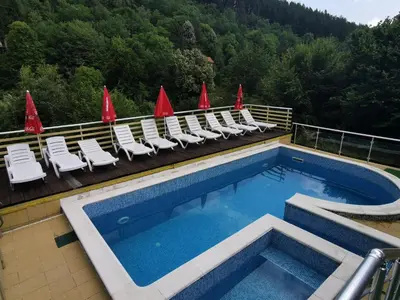 a swimming pool on top of a building with chairs at Guest House Shipkovo Hills in Shipkovo
