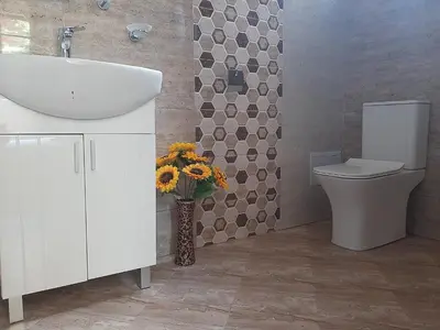 a bathroom with a sink and a toilet and a vase of flowers at Вила Мая 2 in Krayni Dol