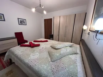 a bedroom with a bed with two red pillows on it at Апартамент Планинско Гнездо - Mountain Nest in Stoykite