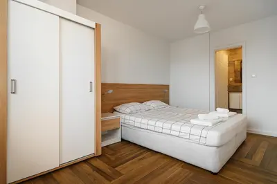 a white bedroom with a bed and a mirror at South Panoramic Apartment in the art district of Kapana in Plovdiv