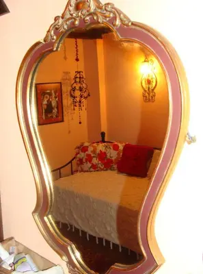 a bedroom with a bed in a large mirror at Старата къща / село Тъжа in Tŭzha