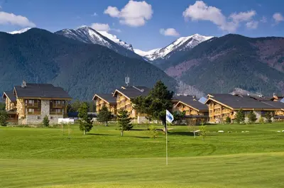 a golf course with a resort and mountains in the background at Pirin Golf Hotel Private Studios - Sani, Bansko in Razlog