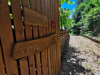 a fence with writing on it next to a dirt road at Вила Край реката in Botevgrad