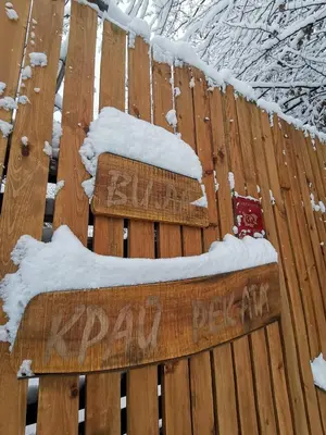 a sign on a wooden fence with snow on it at Вила Край реката in Botevgrad