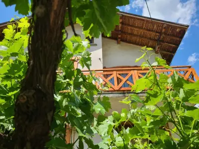 a building with a wooden balcony with a tree at Вила 111 in Sapareva Banya