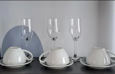 a table with three wine glasses and saucers and plates at Студио Цвят/ Studio Colour in Blagoevgrad