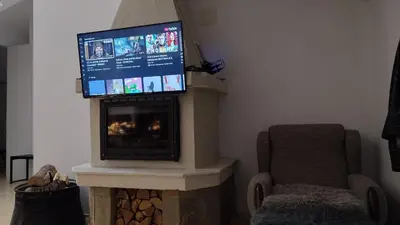 a living room with a flat screen tv above a fireplace at Pearl XL in Pamporovo