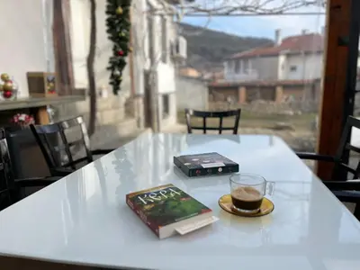 a table with a book and a glass of coffee on it at Къща Христини in Kalofer