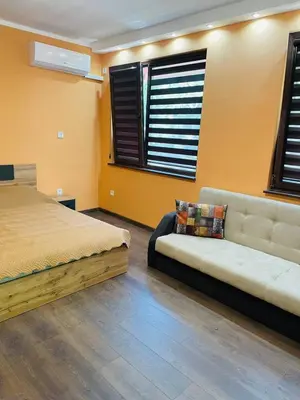 a bedroom with a bed and a couch and windows at Къща за гости Станеви in Ribarica