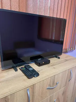 a television on a wooden cabinet with a remote control at Къща за гости Станеви in Ribarica