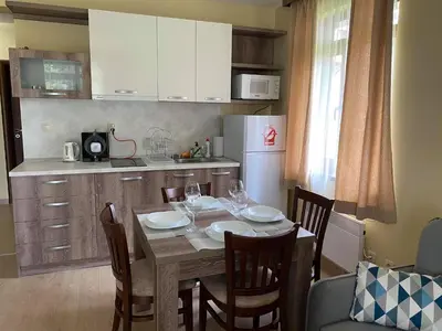 a kitchen with a table and chairs and a kitchen with white cabinets at Апартамент в MountainLake in Smolyan
